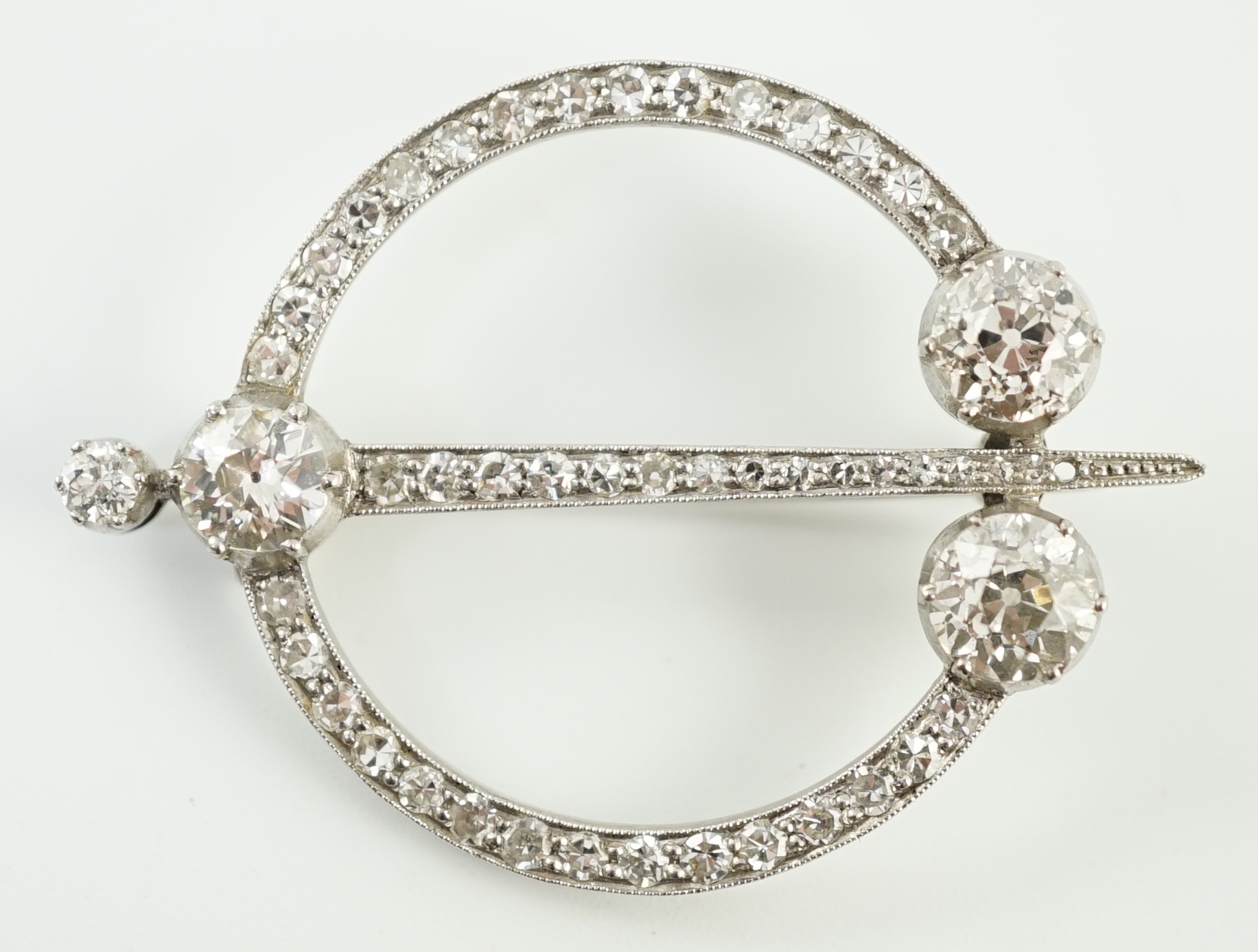 A 1920's platinum or white gold, diamond cluster set openwork 'dagger and circle' brooch